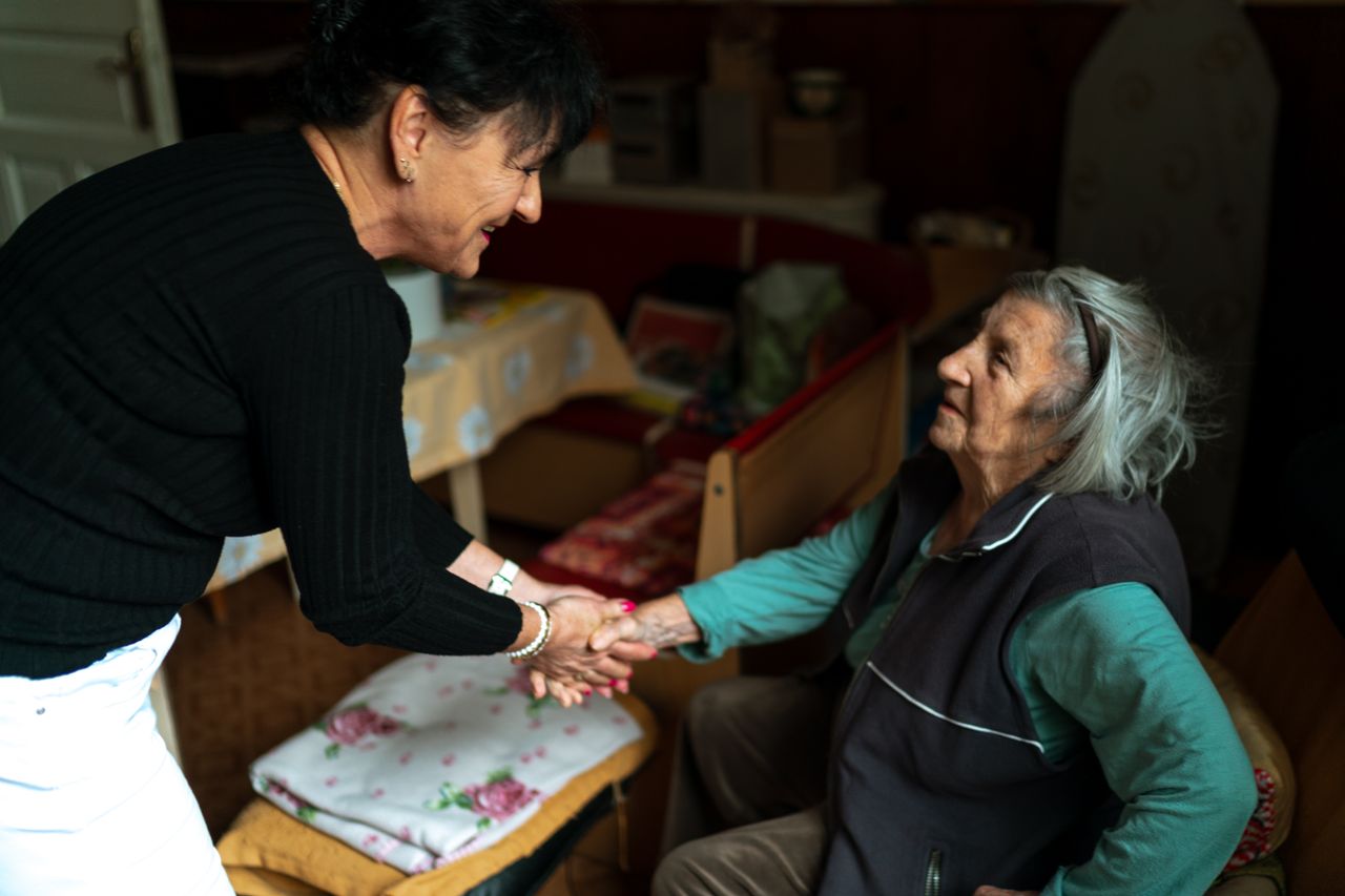 A caregiver holding a senior woman's hands, offering calm and gentle reassurance