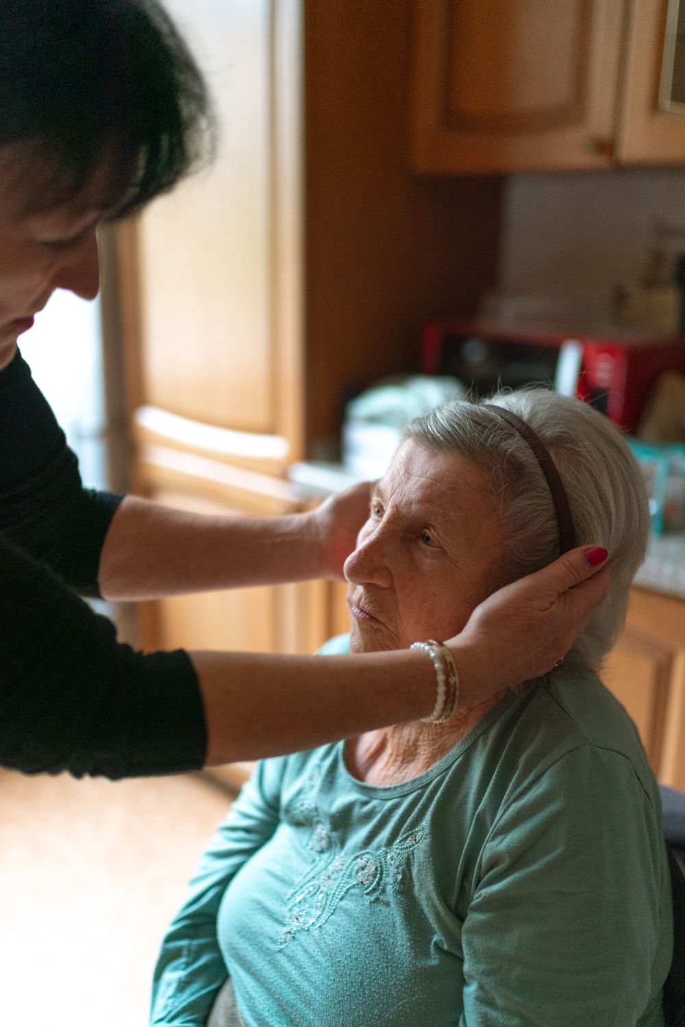 A caregiver gently supporting a senior woman with a calm, reassuring touch at home